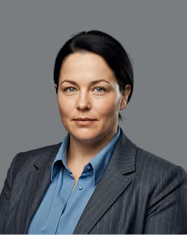 Professional woman with dark hair wearing a blue shirt and pinstripe blazer against gray background.
