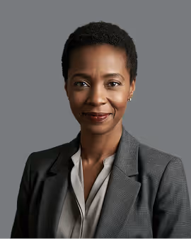 Smiling professional woman with short hair wearing a gray blazer and beige blouse against a gray background.