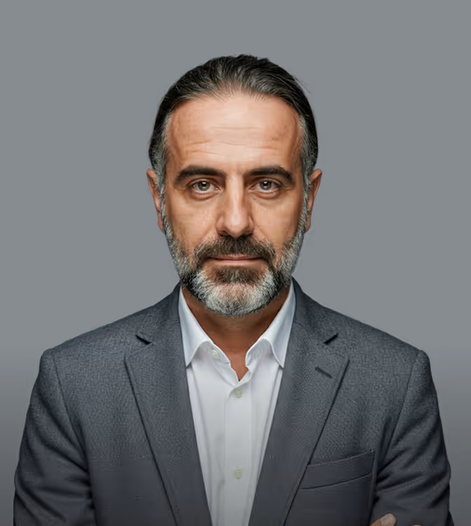 Middle-aged man with gray beard and slicked-back hair wearing a gray suit and white shirt.
