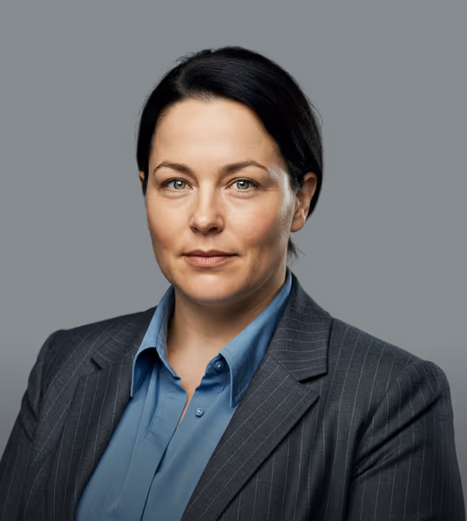 Professional woman with dark hair wearing a blue shirt and pinstripe blazer against a dark background.